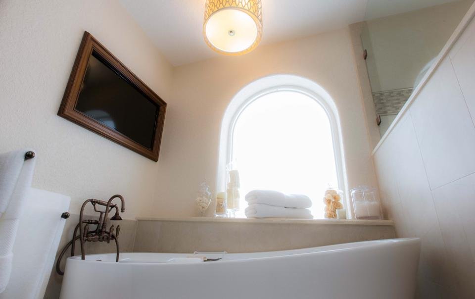 Bathroom with freestanding tub beneath arched window