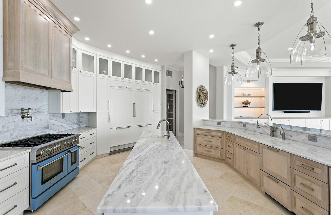 White kitchen with marble island and pendant fixtures